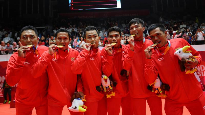 Indonesia men's badminton team - Indonesia 2018 a group of Indonesian male Para badminton players biting their gold medals