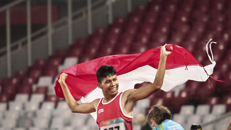 Sapto Yogo Purnomo - Indonesia 2018 male Para athlete Sapto Yogo Purnomo running holding an Indonesia flag