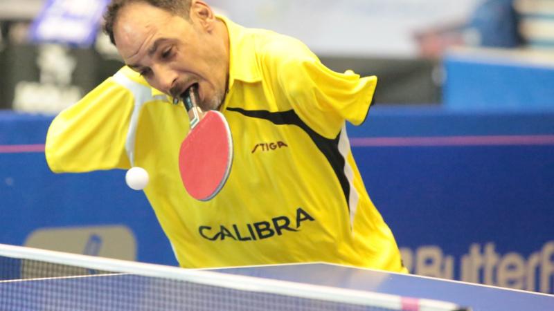 Ibrahim Hamadtou - Egypt - table tennis Egyptian male table tennis player holds racket in mouth and attempts to hit the ball