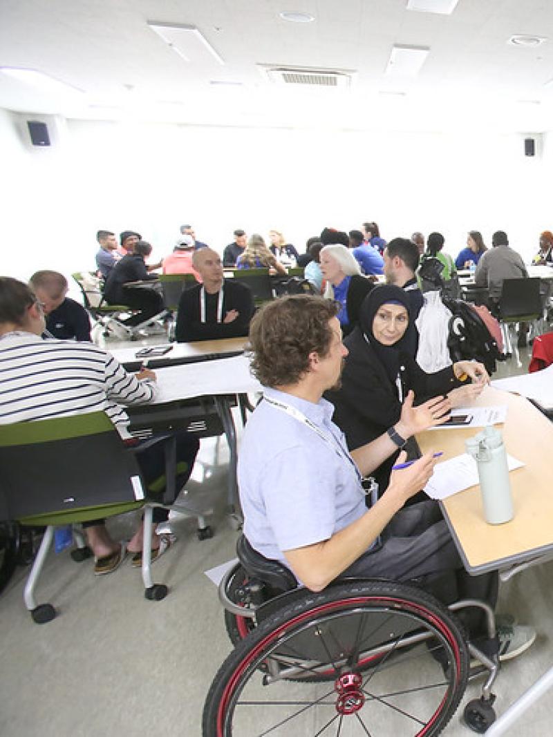Nine athletes gather around a table for a discussion during the athletes' forum in 2023