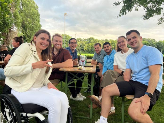Seven athletes sitting around a table and smiling at the camera